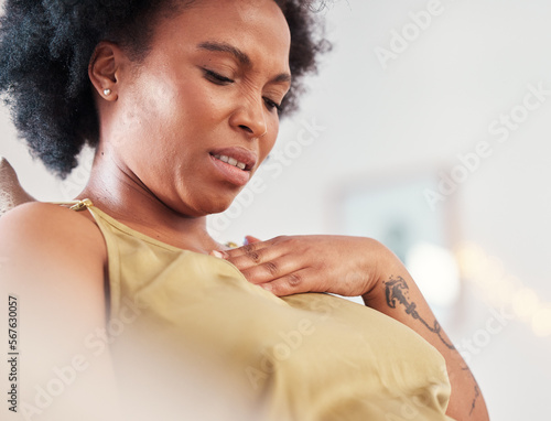 Pregnant black woman, heartburn and pain in home with cramps and stressed expression on face. Pregnancy, labour contractions and mother with ache or medical emergency in apartment with hand on chest. photo