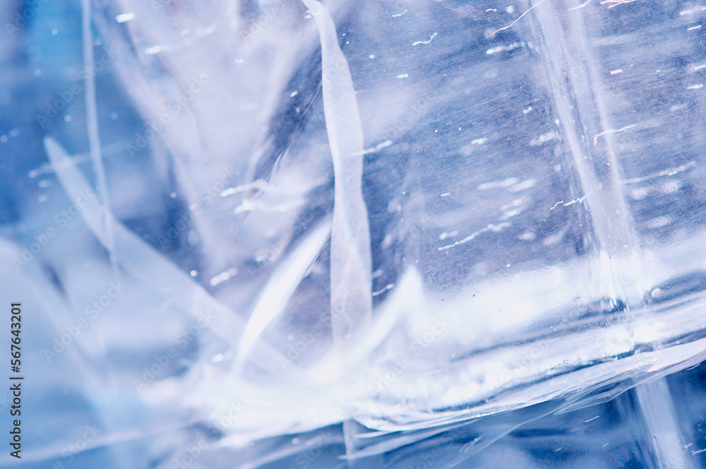 Bubbles and cracks inside natural ice. Geometric wavy pattern of glare and light distortion. Abstract background. Close up. Selective focus. Bubbles and cracks inside natural ice. Geometric wavy pattern of glare and light distortion. Abstract background. Close up. Selective focus.