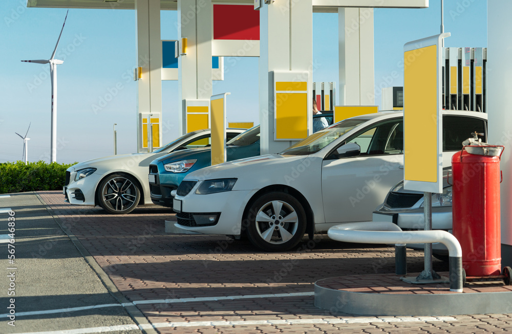 Fototapeta premium Cars on a gas station with wind turbines on a background