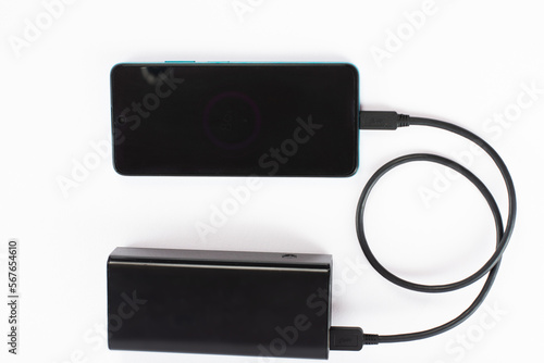 power bank with charging cable and phone, copy space and white background.