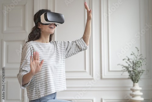 Young happy woman in virtual reality headset enjoying fun shopping experience in augmented world