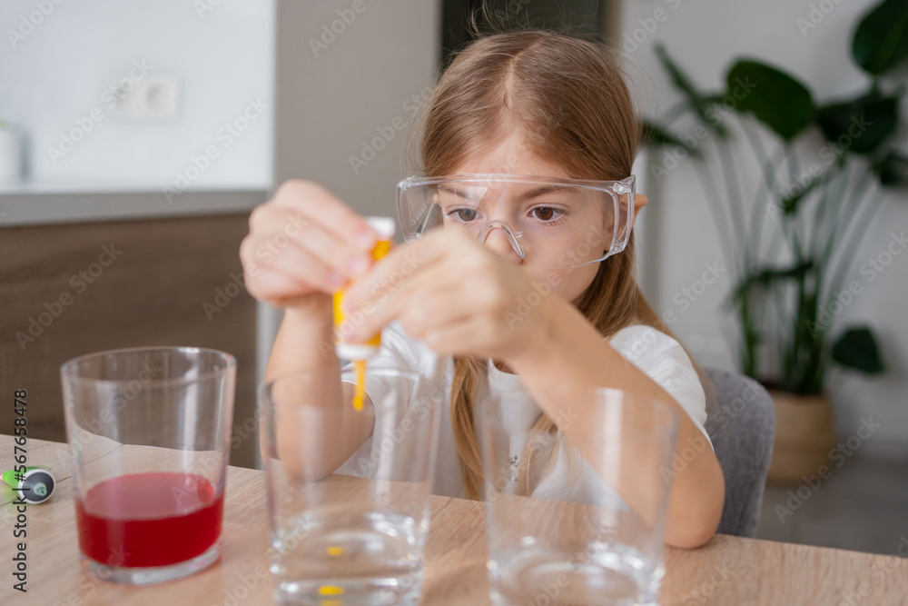 child learning research and doing a chemical experiment while making analyzing and mixing liquid in test glasses. Playful little girl in protective wear having fun playing with chemistry lab game. child learning research and doing a chemical experiment while making analyzing and mixing liquid in test glasses. Playful little girl in protective wear having fun playing with chemistry lab game.