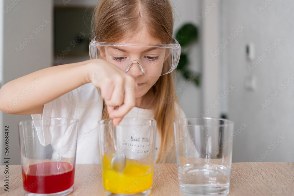 child learning research and doing a chemical experiment while making analyzing and mixing liquid in test glasses. Playful little girl in protective wear having fun playing with chemistry lab game. child learning research and doing a chemical experiment while making analyzing and mixing liquid in test glasses. Playful little girl in protective wear having fun playing with chemistry lab game.