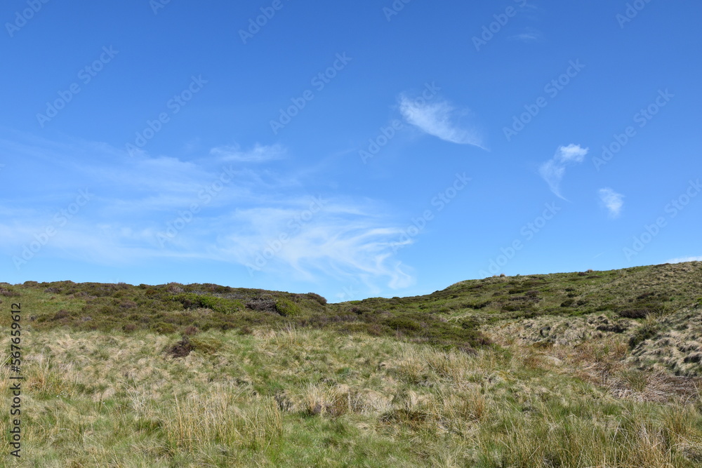 Hiking in the green countryside with a blue sky background and no people. 