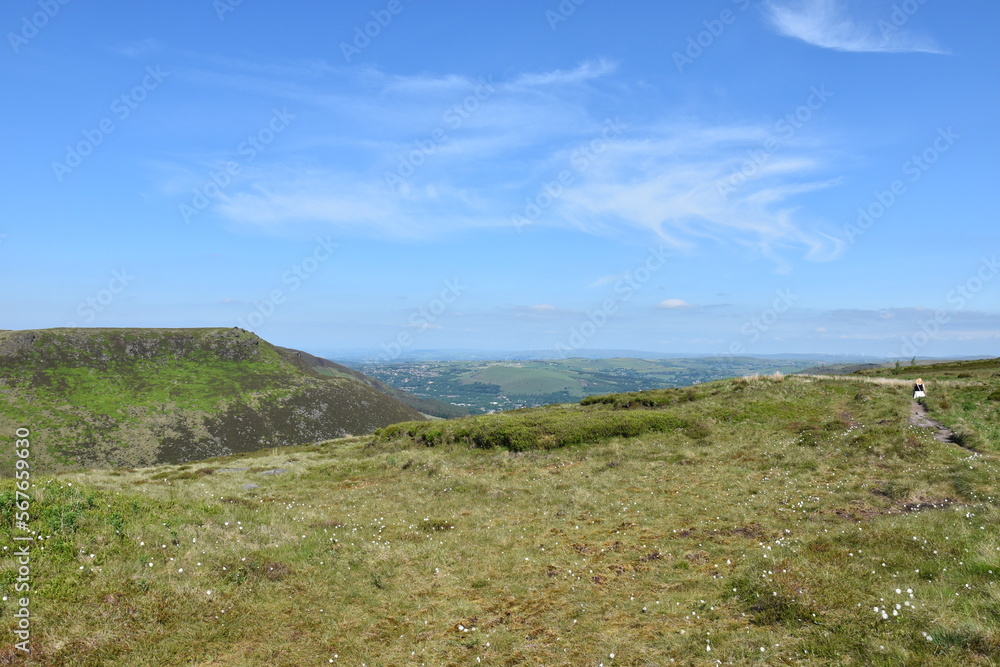 View from the top of a mountain with green fields and a blue sky background. Taken in Oldham England. 