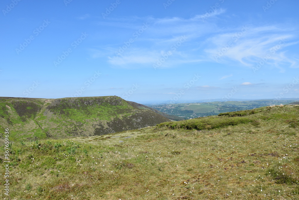 View from the top of a mountain with green fields and a blue sky background. Taken in Oldham England. 