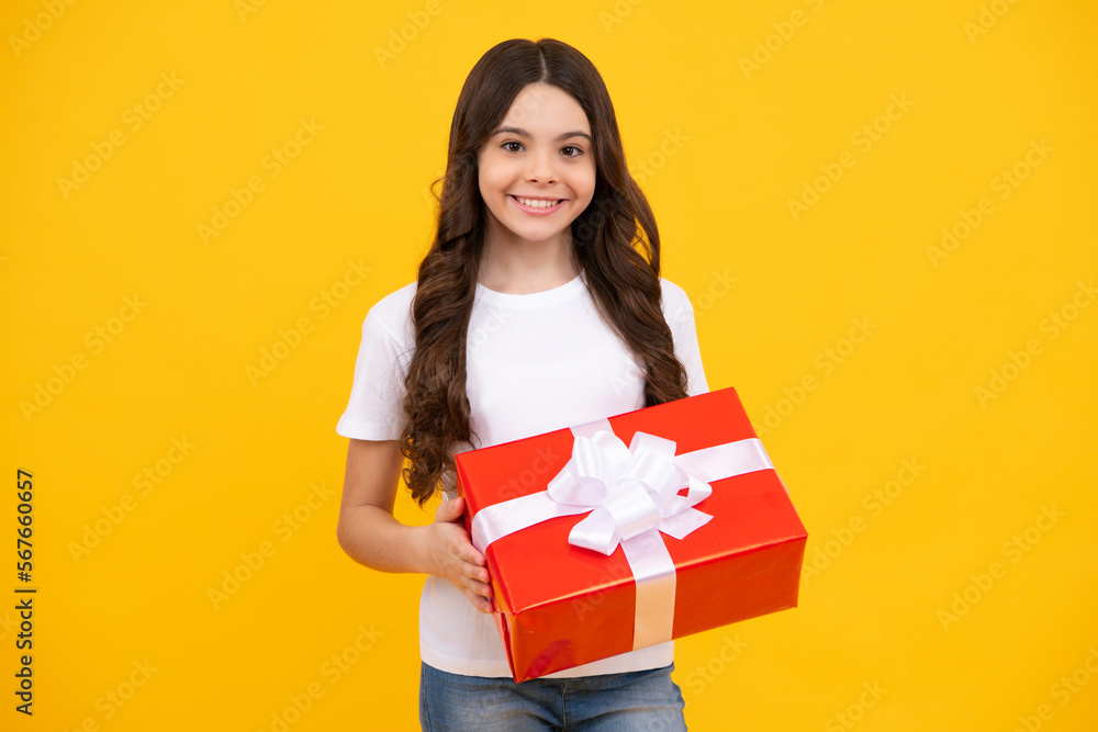 Happy teenager, positive and smiling emotions of teen girl. Teenager child in t shirt holding gift box on yellow isolated background. Gift for kids birthday. Summer holiday. Happy teenager, positive and smiling emotions of teen girl. Teenager child in t shirt holding gift box on yellow isolated background. Gift for kids birthday. Summer holiday.