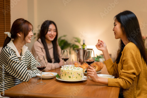 Young smiling woman drinking and clinking glass of wine to toasting with happiness while celebrating in new year party at home