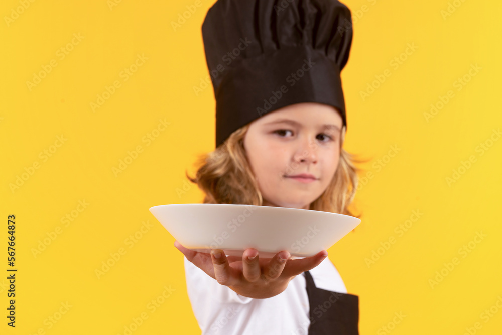 Funny child cook with cooking plate. Child in cook uniform. Chef kid isolated on yellow background. Cute child to be a chef. Child dressed as a chef hat. Funny child cook with cooking plate. Child in cook uniform. Chef kid isolated on yellow background. Cute child to be a chef. Child dressed as a chef hat.