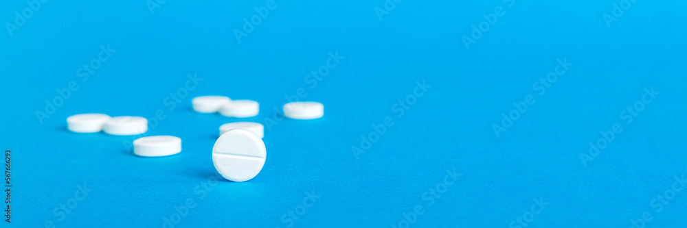 Heap of white pills on colored background. Tablets scattered on a table. Pile of red soft gelatin capsule. Vitamins and dietary supplements concept