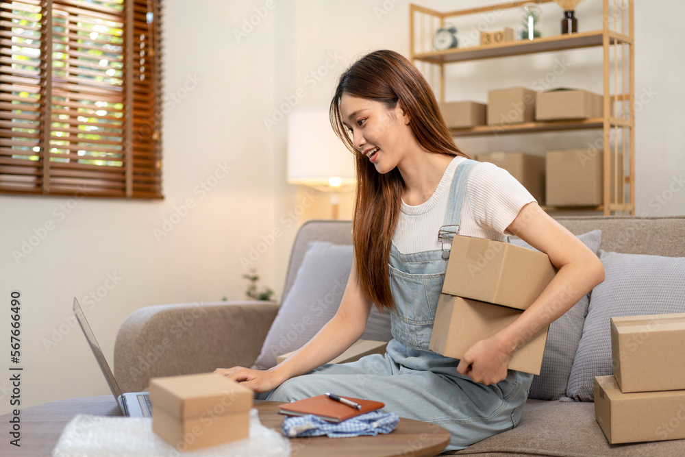 Obraz premium Young entrepreneur is using laptop to checking online orders and