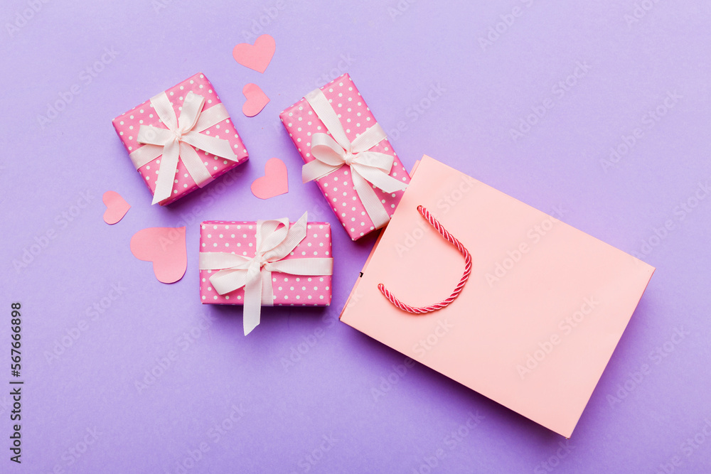 Gift boxes pop out from paper bag top view on colored background. bag packing handmade boxes fall out Concept of holidays, shopping, sale, discounts. Top view, flat lay Gift boxes pop out from paper bag top view on colored background. bag packing handmade boxes fall out Concept of holidays, shopping, sale, discounts. Top view, flat lay