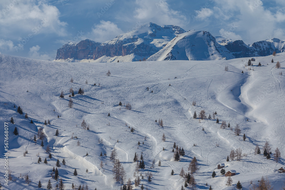 Traces of skiers and snowboarders on white snowy meadows of Fedare. In the background the majestic walls of the Sella Massif. Giau Pass, Dolomites, Italy