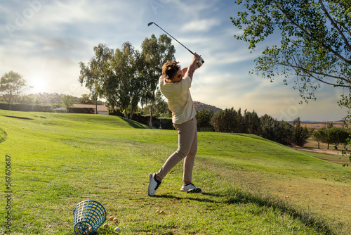 golf driving range on natural grass. golfer having fun on the driving range practicing his swing with an iron. Golf driving range on natural grass. golfer struck with iron