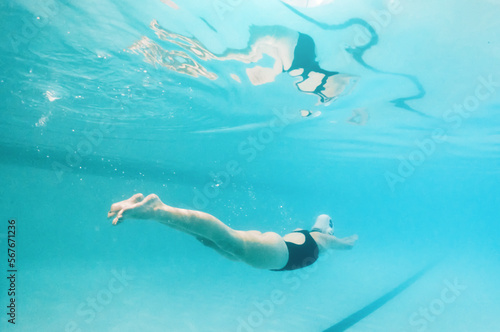 Swimming, fitness and sports with a woman underwater in a pool for cardio or endurance exercise. Water, swimwear and health with a female swimmer during a workout or competitive watersports game