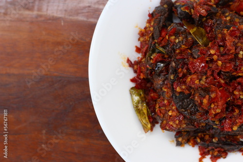 A plate of Fried Cow Lungs Spicy, commonly called in Indonesia 'Paru Goreng Balado', Indonesian Traditional Food from Padang, West Sumatera on a wooden table.  Half view from above