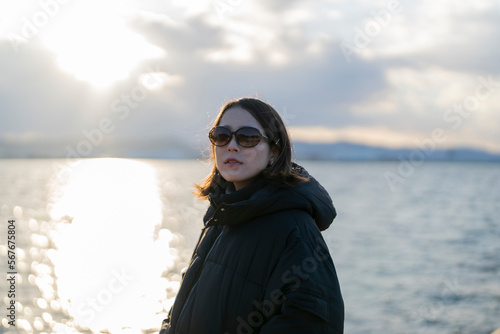 夕暮れの海でサングラスをしている女性 © peach100