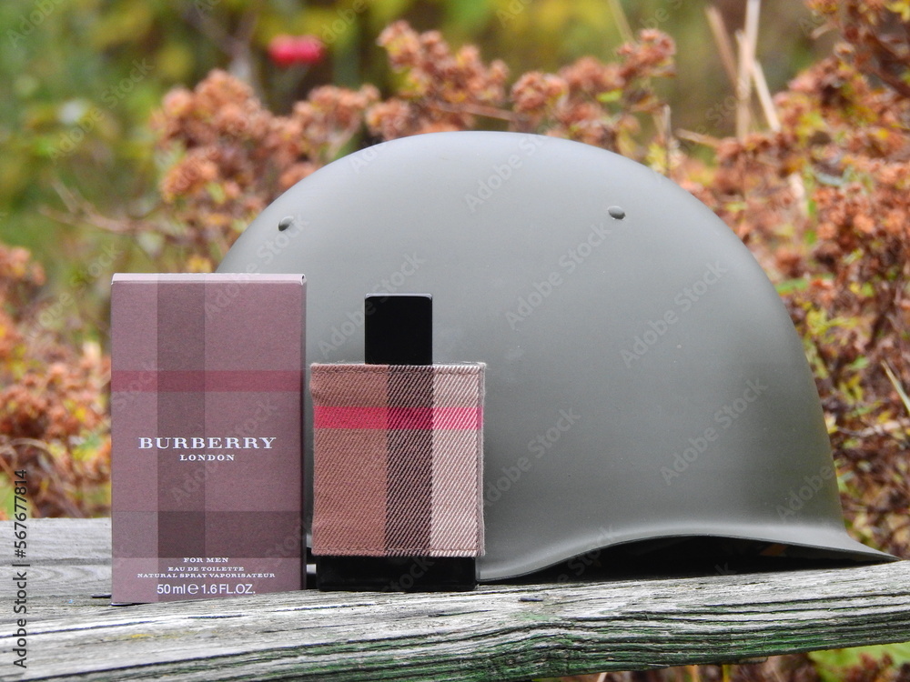 Fototapeta premium Bottle of Burberry London eau de toilette with a 1960s steel helmet and other Russian militaria, Taldom, Russia - October 31, 2020