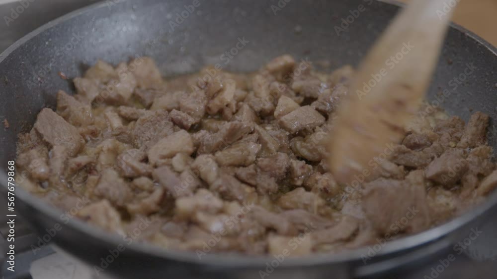 stirring meat in a frying pan on the stove stirring meat in a frying pan on the stove