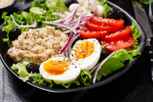 Healthy breakfast. Savory oatmeal with fresh cucumber, tomatoes, olives, lettuce, mozzarella cheese and boiled egg. Top view