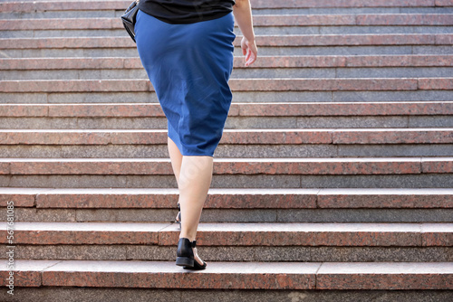 Woman in blue skirt going up the stairs. Female legs in shoes on steps, ladies fashion and footwear in city