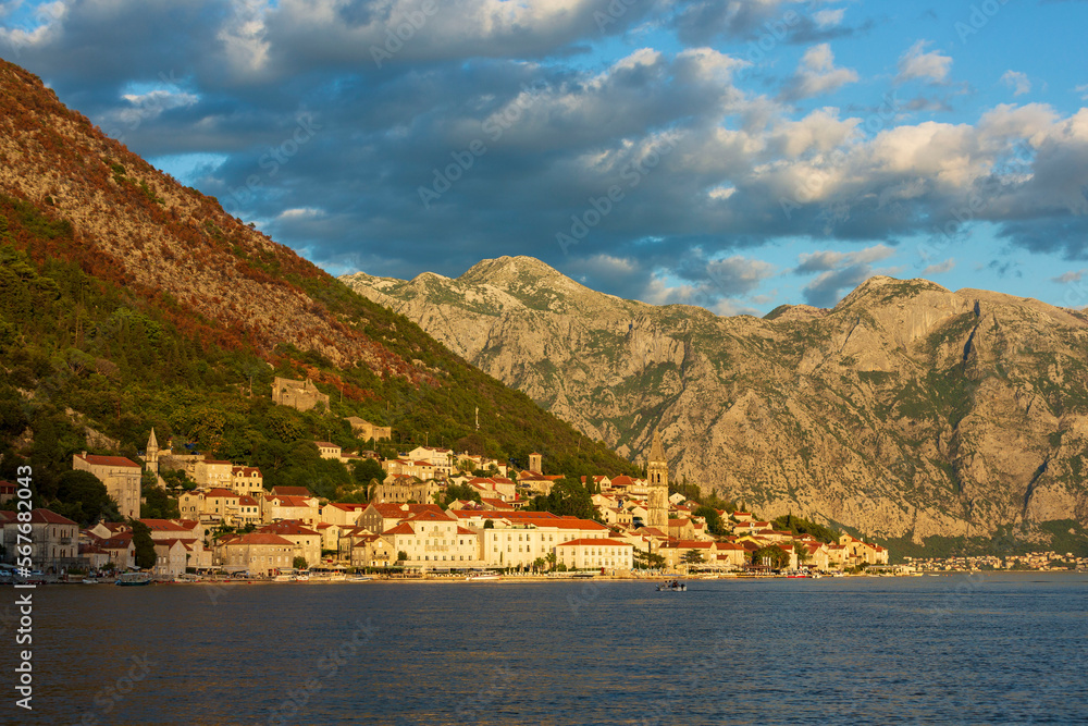 Seaside town in the rays of the setting sun against the backdrop of majestic mountains. Bay of Kotor, Montenegro