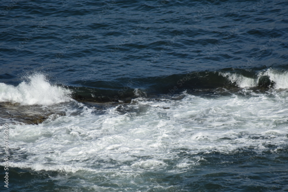 Fototapeta premium Aerial view looking down onto waves crashing onto rocks. North Berwick Scotland.