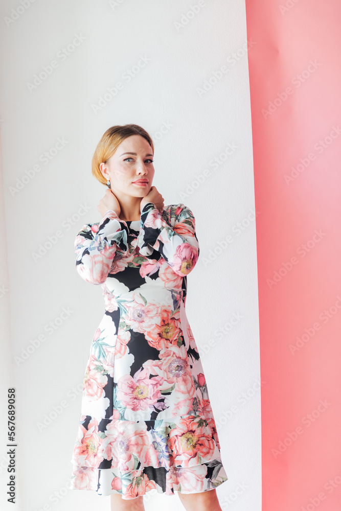 a beautiful woman in a floral dress poses on a white background a beautiful woman in a floral dress poses on a white background