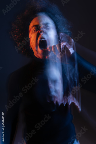 double exposure of abused african american man with bipolar disorder and bleeding face screaming on black with orange and blue light