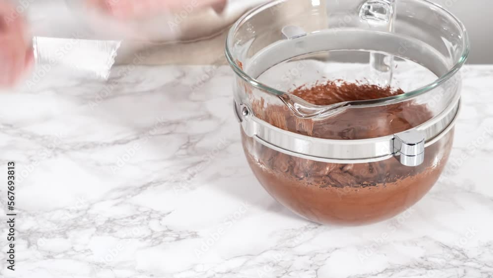 Scooping chocolate ganache frosting into a piping bag with a metal tip. Scooping chocolate ganache frosting into a piping bag with a metal tip.