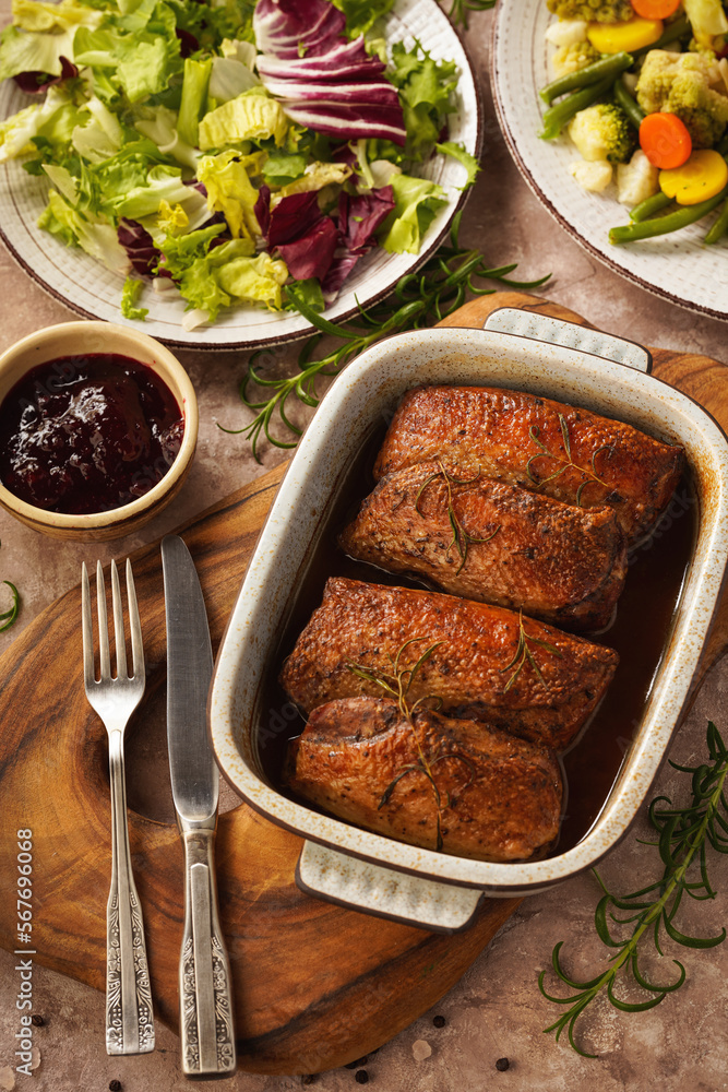 Roasted duck breasts served with vegetables and cranberry dip.