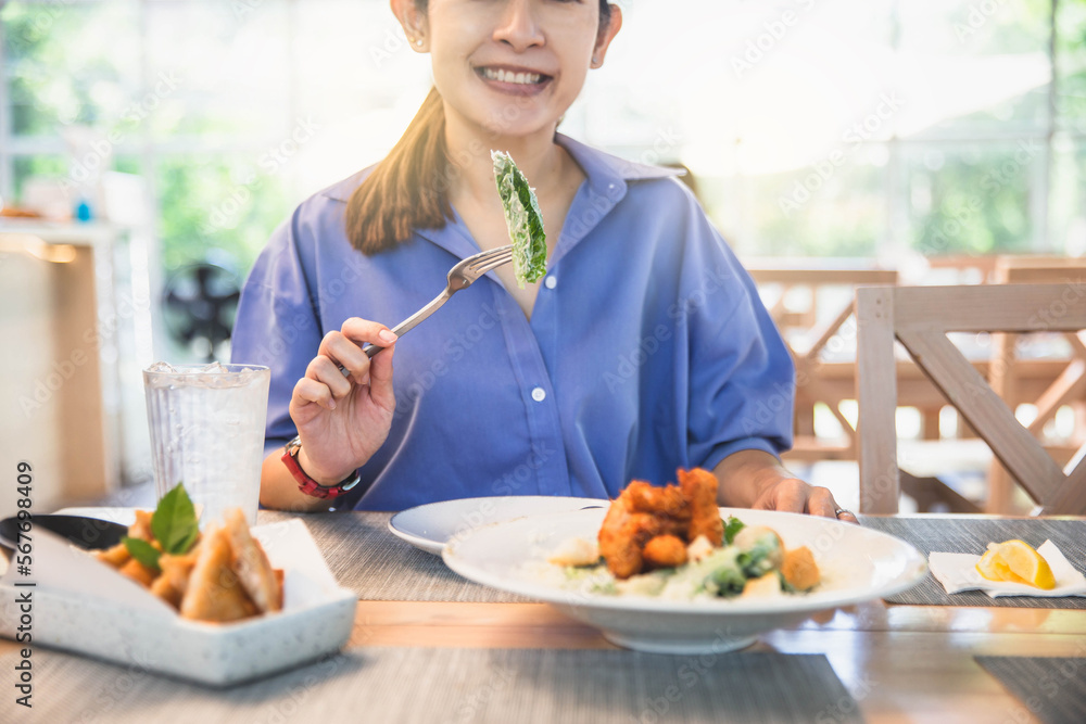 Young and happy woman eating healthy salad on wooden table. Beautiful smiling woman eating healthy salad. Young and happy woman eating healthy salad on wooden table. Beautiful smiling woman eating healthy salad.