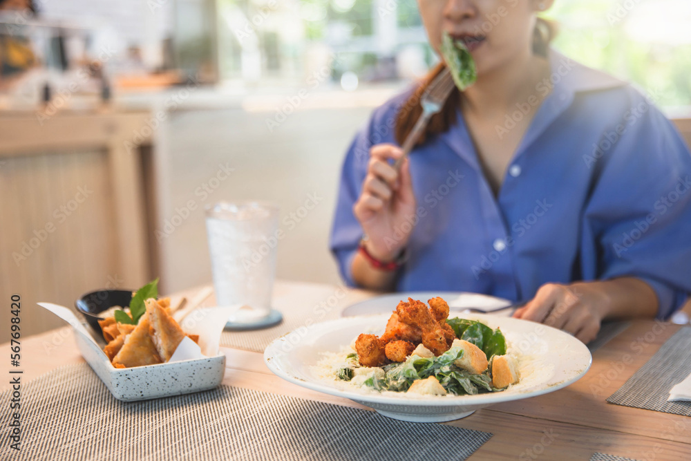 Young and happy woman eating healthy salad on wooden table. Beautiful smiling woman eating healthy salad. Young and happy woman eating healthy salad on wooden table. Beautiful smiling woman eating healthy salad.
