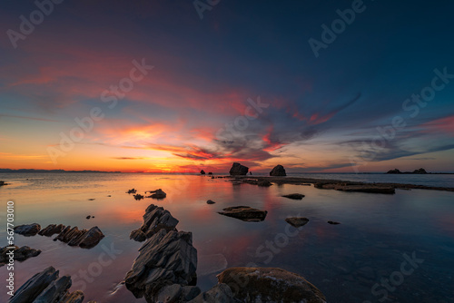 Il sole tramonta dietro gli scogli della spiaggia di Settefrati in provincia di Palermo, Sicilia 