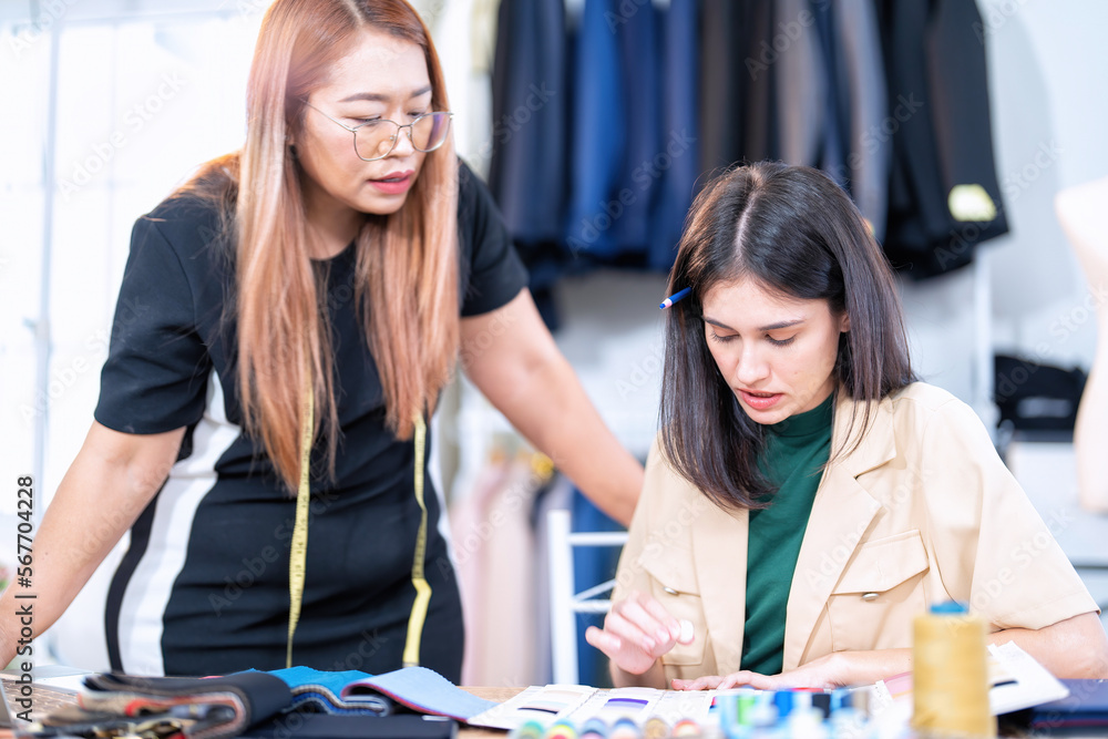 Fototapeta premium Senior fashion designer teamwork discuss teach learner final design share idea in shop lady tailor