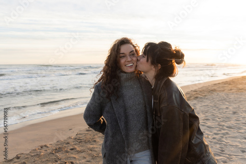 Tableau sur toile Young woman kissing cheek of smiling friend on beach in Barcelona
