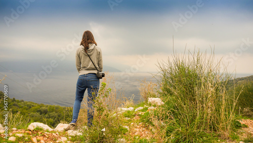 Young brunette woman in jeans watching alone over mediterranean sea, vanlife, Croatia