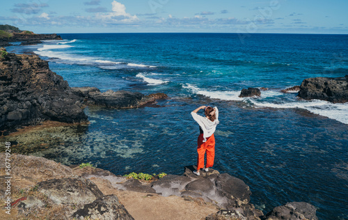 Lonely woman dressed light summer clothes enjoying Indian ocean view with strong surf on cliff at Gris Gris viewpoint extreme south of Mauritius island. Traveling around the world concept image. photo