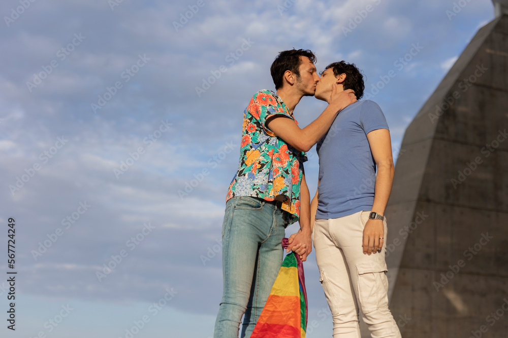 Happy young couple with rainbow flag. Two men enjoy outside.. Happy young couple with rainbow flag. Two men enjoy outside..