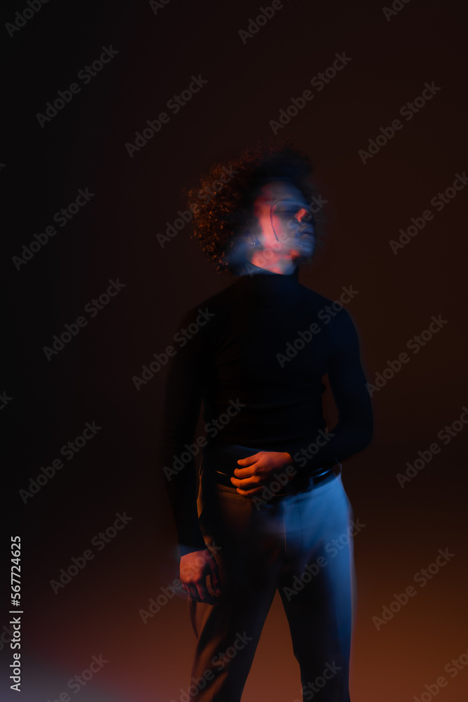 motion blur of african american man with bipolar disorder and injured face standing on dark background with orange and blue light