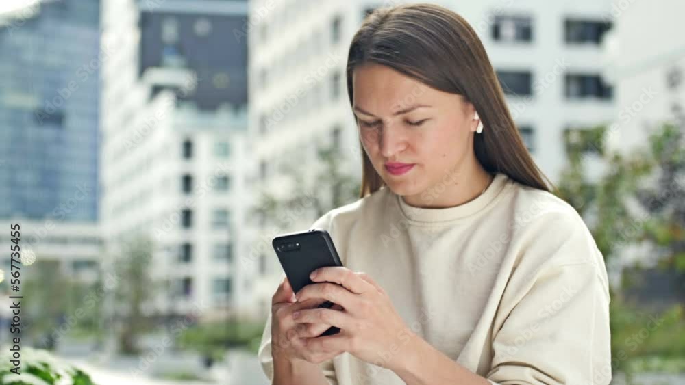 Young attractive woman with wireless headphones in her ears listens to music through a mobile phone. Modern European city, summer day. A woman dances to the beat of the music. Young attractive woman with wireless headphones in her ears listens to music through a mobile phone. Modern European city, summer day. A woman dances to the beat of the music.
