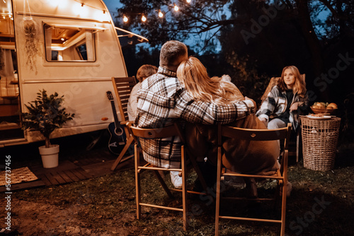 Family trailer travel. Children,brother sister,mom dad fry sausages on fire, eat hot dogs. Evening picnic in nature.Holiday barbecue BBQ food.Vacation weekend dinner.Road lunch.Camper,house on wheels