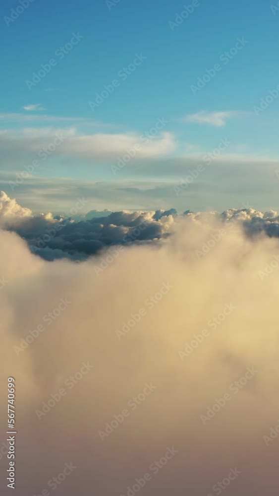 Flying above the clouds. Aerial view of clouds at sunrise. Traveling by air perfect background. Vertical video