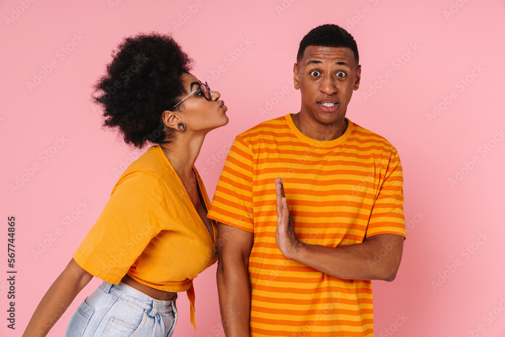 Displeased man gesturing to stop with hand while woman trying to kiss him isolated Displeased man gesturing to stop with hand while woman trying to kiss him isolated