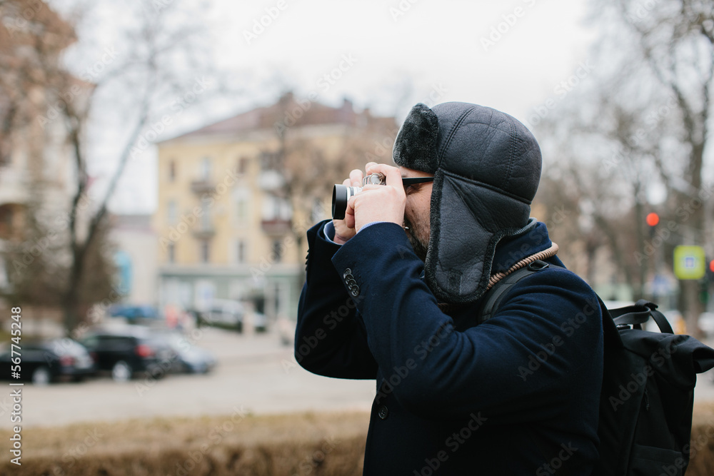 A senior tourist takes pictures of the winter city on his film camera. Travel and hobby concept. A senior tourist takes pictures of the winter city on his film camera. Travel and hobby concept.