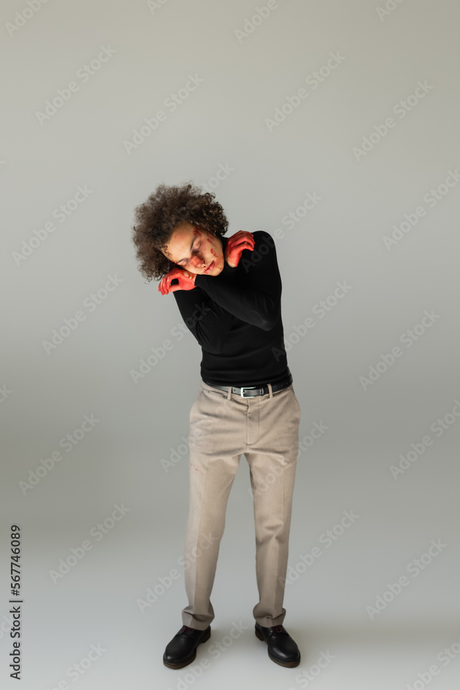 full length of wounded african american man with bleeding face and broken nose standing with closed eyes on grey full length of wounded african american man with bleeding face and broken nose standing with closed eyes on grey