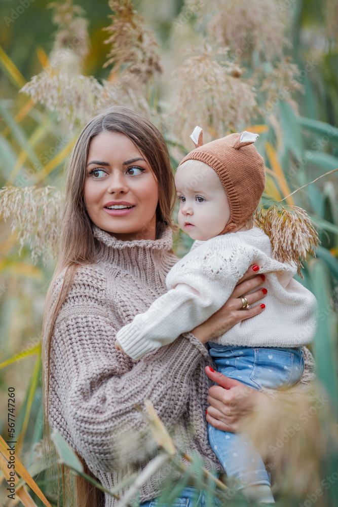 Obraz premium Beautiful young mother with her little daughter 2 years old in green park. Happy family. Cosy.