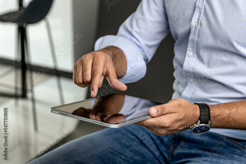 Close up of a man holding and typing on his tablet