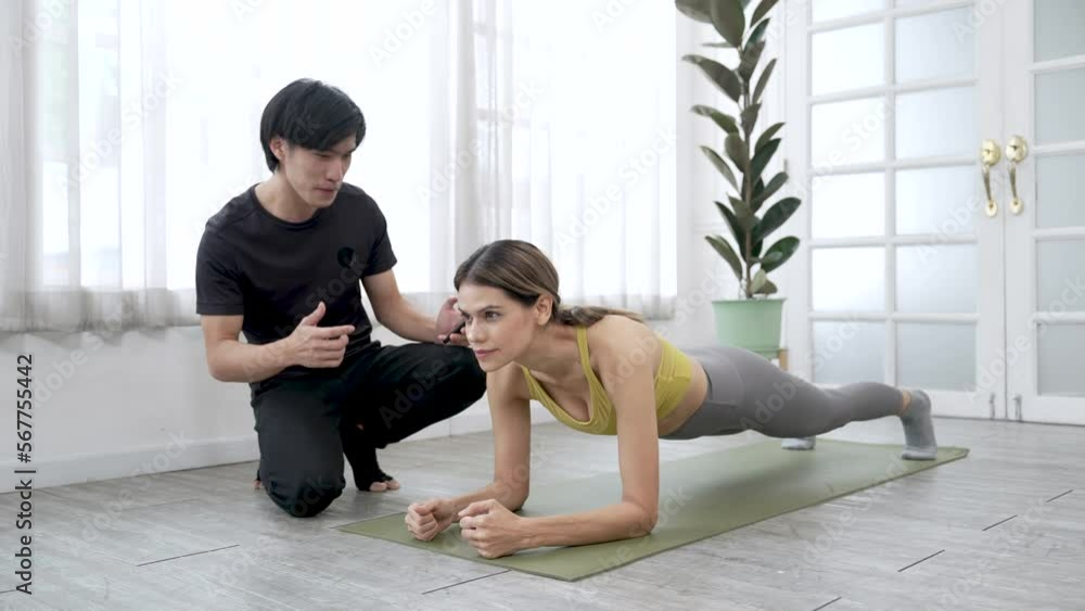 Couple exercising together in the living room at home, Asian male trainer working out with Caucasian woman in gym. Couple exercising together in the living room at home, Asian male trainer working out with Caucasian woman in gym.
