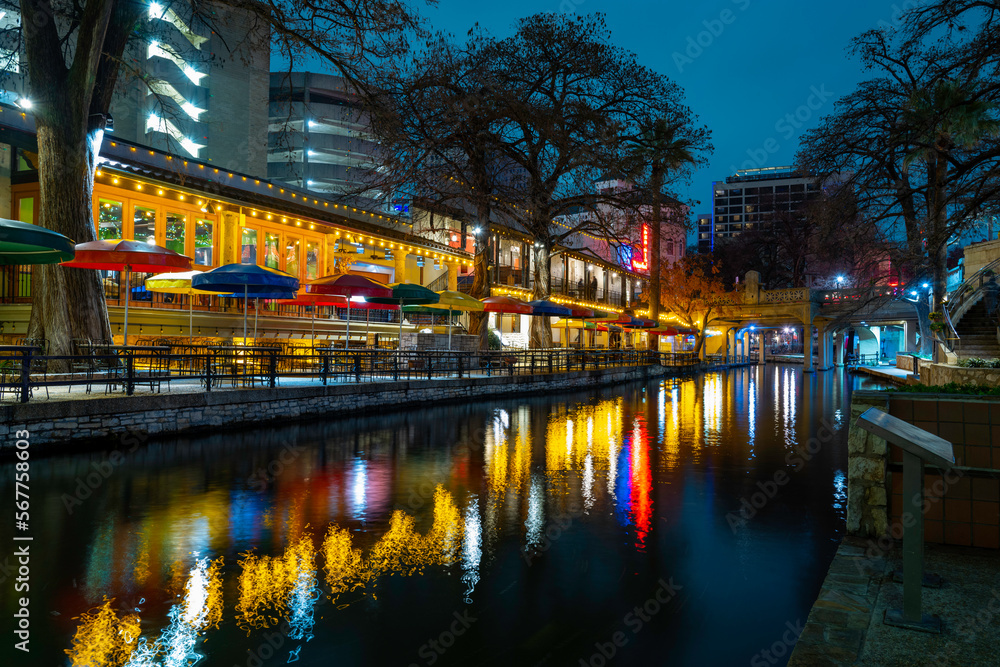 San Antonio River Walk nightscape over the canal footpath illuminated by the vibrant lights and water reflections in winter, Texas, USA